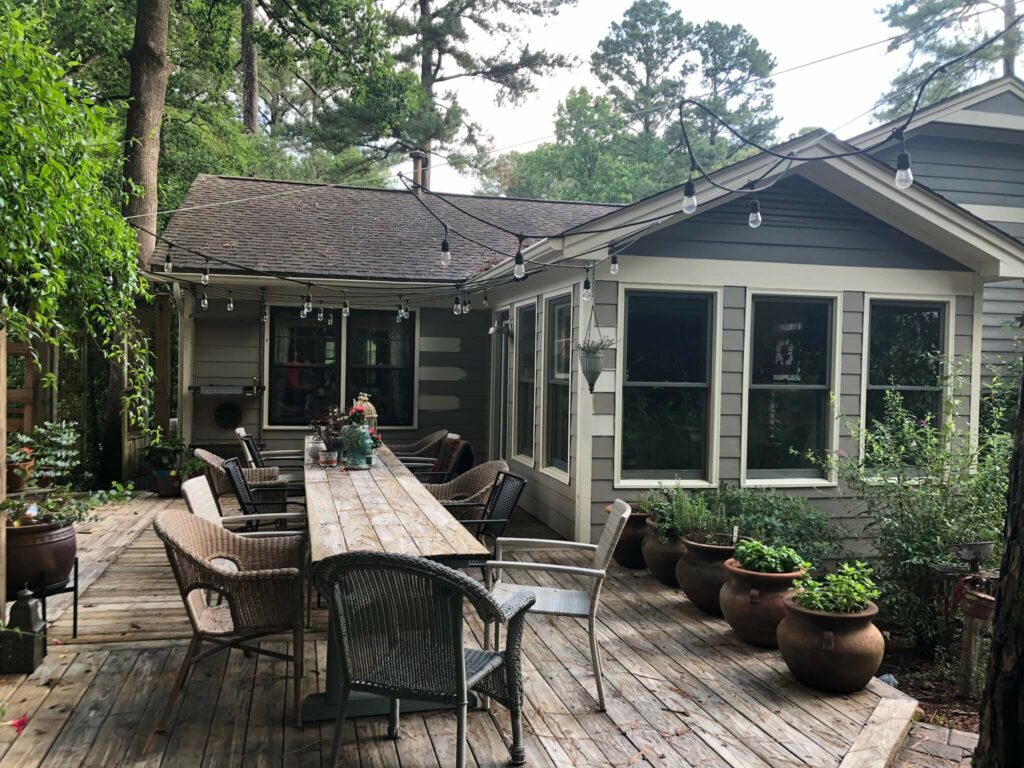 a house with a table and chairs on a deck before before paint refresh
