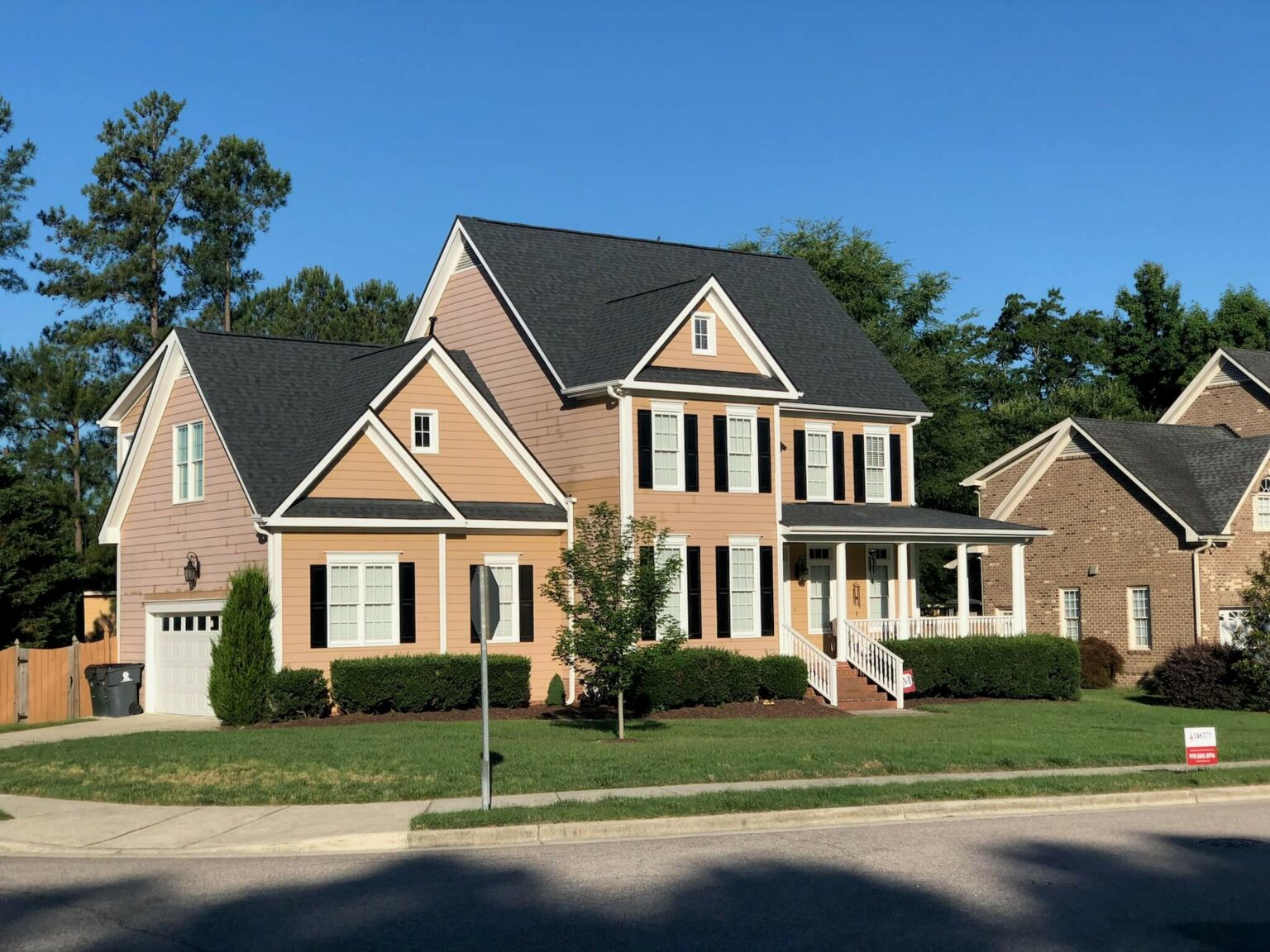 Two-story home with tan siding before an Oak City Coatings exterior repaint