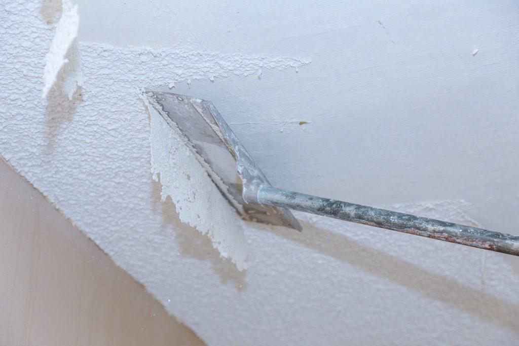 Removing popcorn ceiling from ceiling with a tool