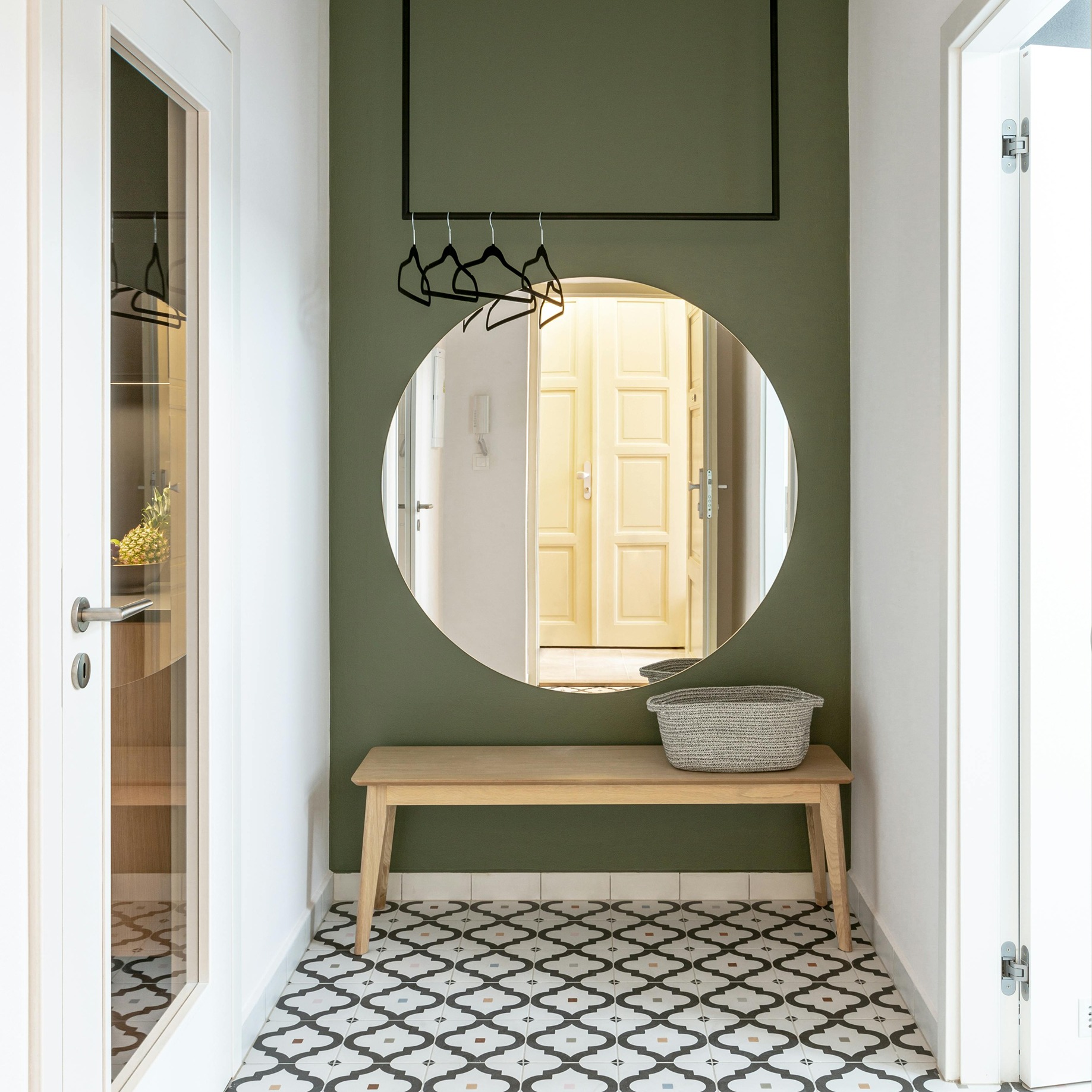 green painted accent wall in bathroom with white and green tiles