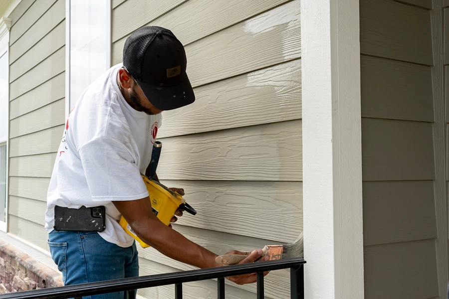oak city coatings crew member painting exterior of house with paint brush in Fuquay-Varina